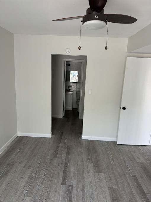 A room with a ceiling fan and a doorway leading to another room.