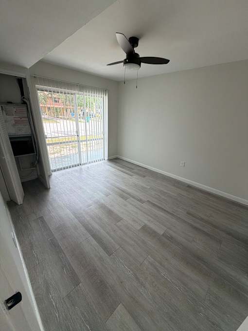 A room with a ceiling fan and sliding glass doors.