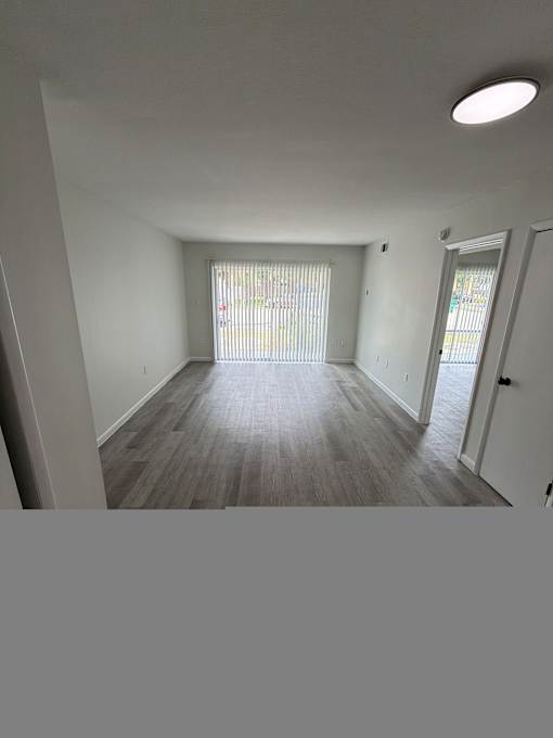 A room with a window and a wooden floor.