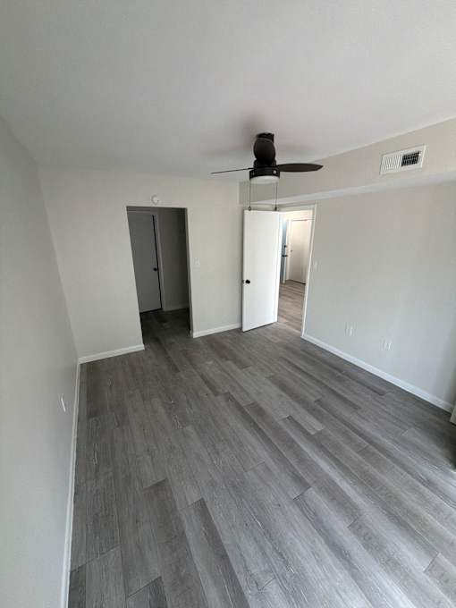 A room with a ceiling fan and a doorway leading to another room.