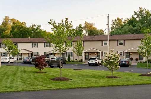A parking lot in front of a building with cars parked.