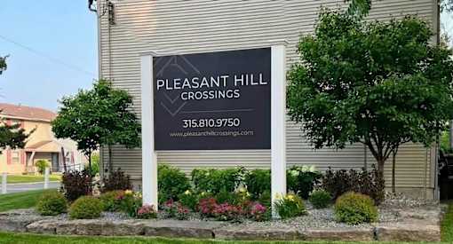 A sign for Pleasant Hill Crossings with a phone number and website.
