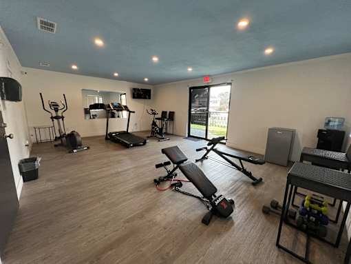 A spacious gym with a variety of equipment including treadmills, weights, and benches.