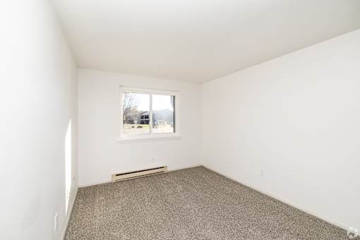 A room with a window and a car parked outside.