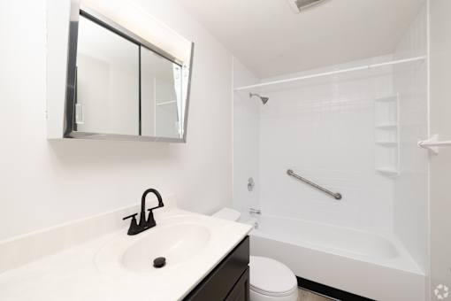 A white sink with a black faucet and a mirror above it.