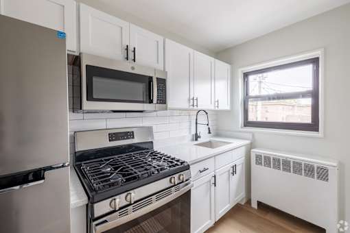 A white kitchen with a stove, oven, microwave, and refrigerator.