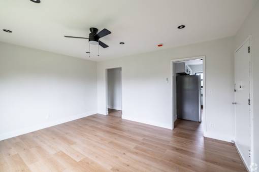 A room with a ceiling fan and wooden flooring.