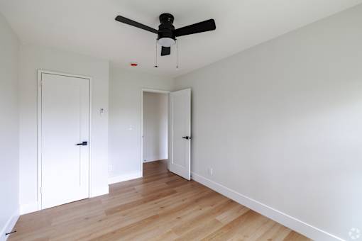 A room with a ceiling fan and wooden floors.