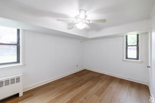 A room with a ceiling fan and wooden flooring.