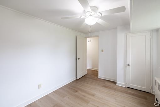 A room with a ceiling fan and wooden floors.