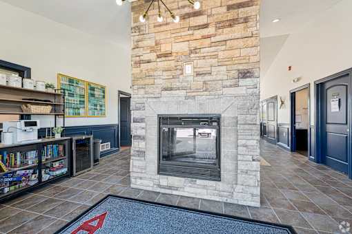A stone fireplace in a room with a blue rug on the floor.