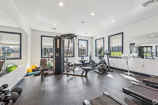A spacious gym with a variety of equipment including a treadmill, exercise bike, and weight machines.