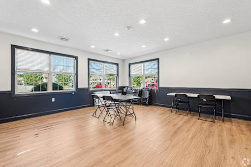 A room with a table and chairs in front of a window.