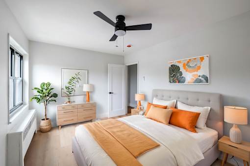 A bedroom with a large bed, a ceiling fan, and a painting on the wall.
