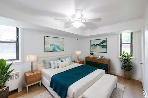 A bedroom with a bed, nightstands, and a ceiling fan.