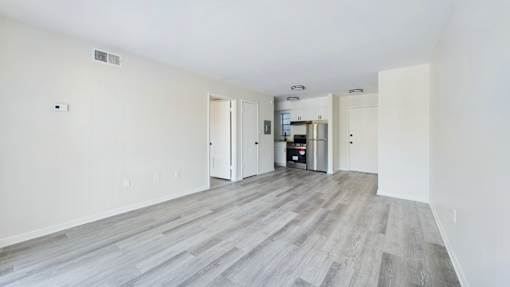 A spacious room with a kitchen area in the background.