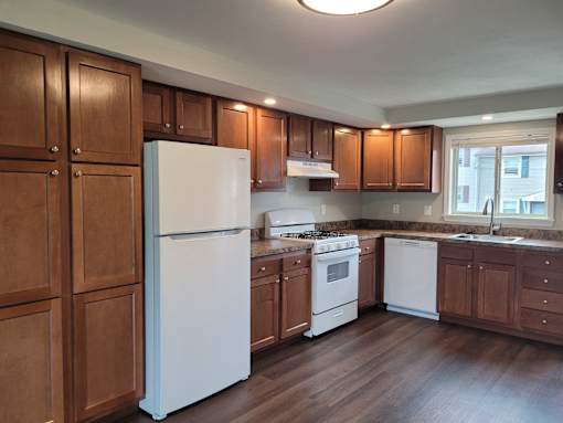 A kitchen with wooden cabinets and white appliances.