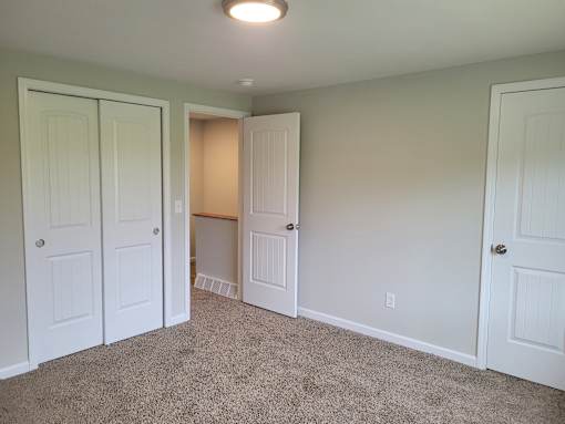 A room with white doors and carpeted floor.