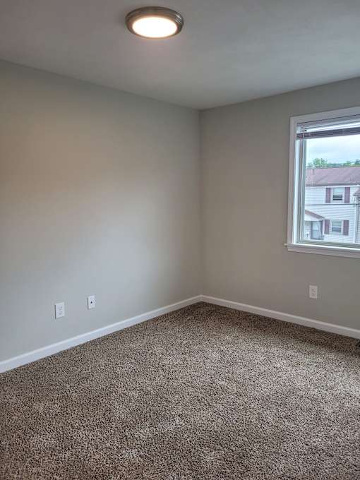 A room with a carpeted floor and a window.