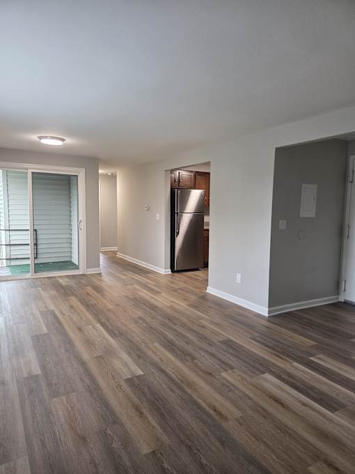 A room with wooden flooring and a refrigerator in the corner.