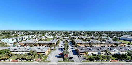 A large, open parking lot is surrounded by a variety of buildings.