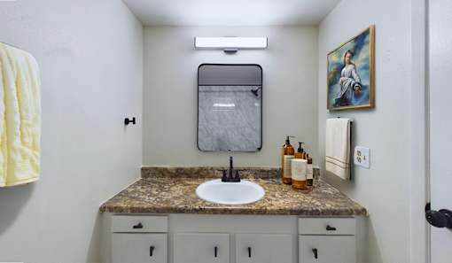 A bathroom with a sink, mirror, and cabinets.