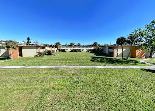 A grassy field with apartment buildings in the background.