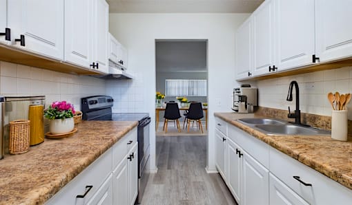 A kitchen with white cabinets and a brown countertop.