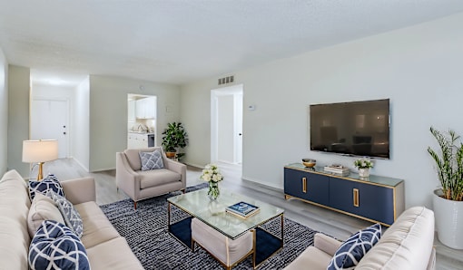 A living room with a white couch, a coffee table, and a TV on a cabinet.