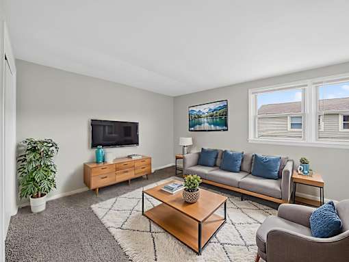 A living room with a grey couch, a wooden coffee table, and a flat screen TV.