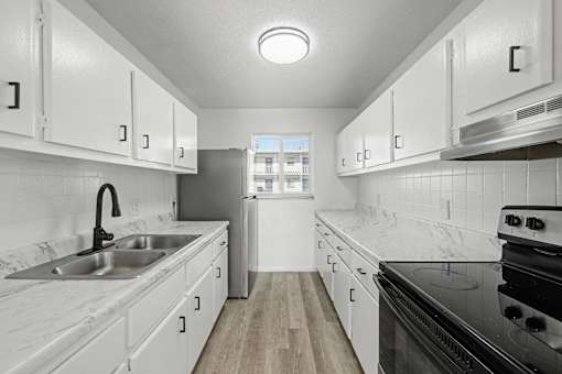 A kitchen with white cabinets and a black stove top oven.