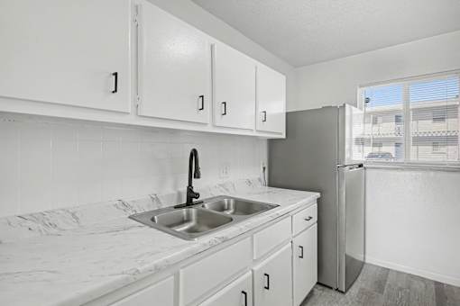 A kitchen with white cabinets and a marble countertop.