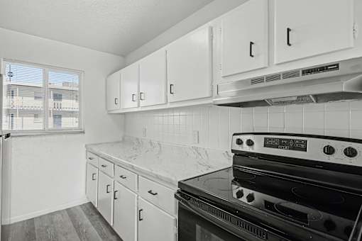A kitchen with white cabinets and a black stove top oven.