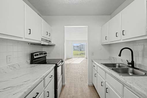 A kitchen with white cabinets and marble countertops.