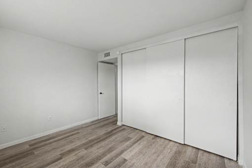 A room with a white wall and a white closet with a door.