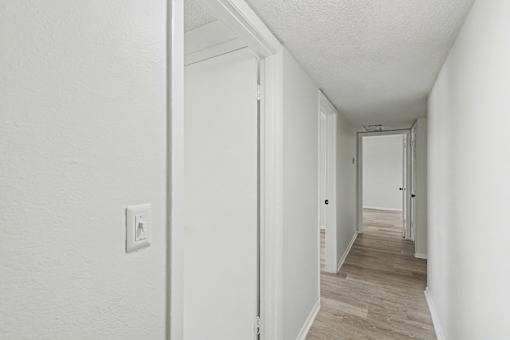 A long hallway with a light switch on the wall.