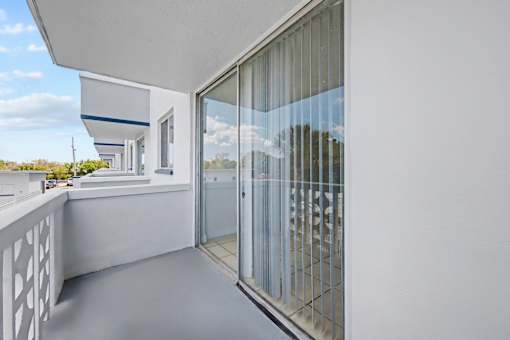 A balcony with a glass door and a white railing.