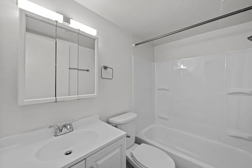 A white bathroom with a toilet, sink, and bathtub.