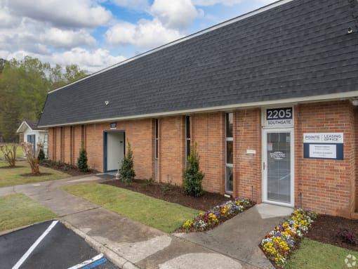 the front of a brick building with a sidewalk and grass