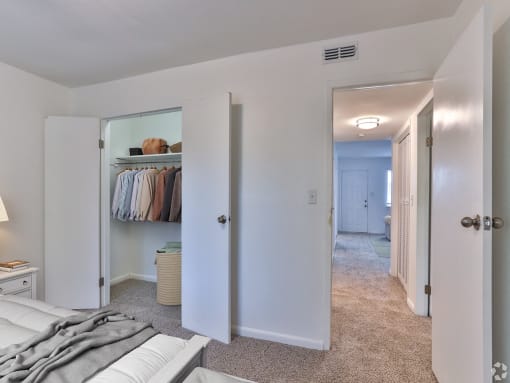 a bedroom with white walls and a hallway with a closet and a bed