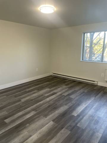 an empty living room with wooden floors and a window