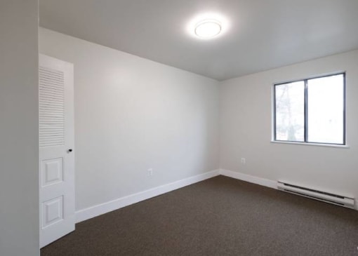 an empty room with white walls and a window