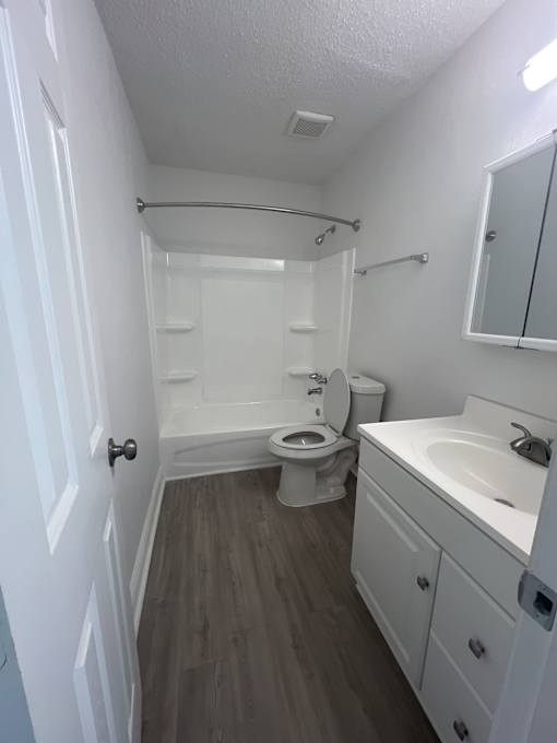 A white bathroom with a toilet, sink, and shower.