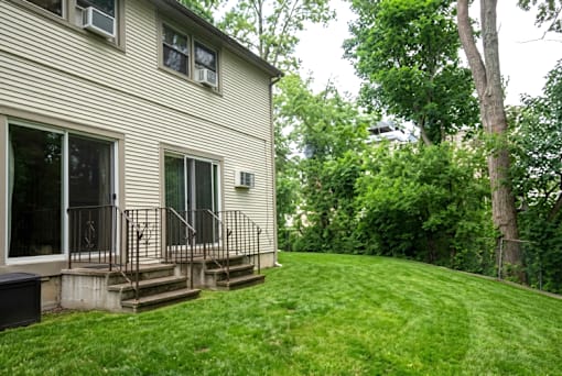 A house with a green lawn and trees in the background.