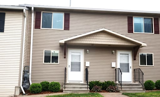 A beige house with a white door and a small porch.