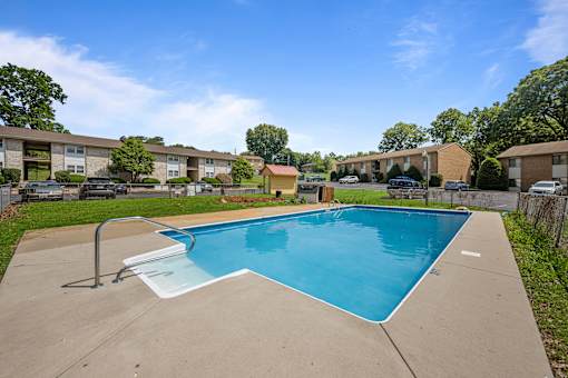 A swimming pool in a residential area with apartment buildings in the background.
