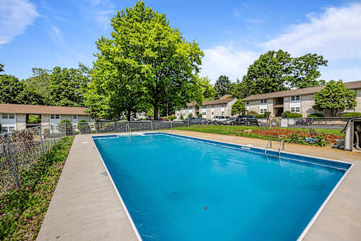 A blue swimming pool surrounded by a fence and trees.