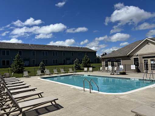 A swimming pool surrounded by sun loungers and a building in the background.