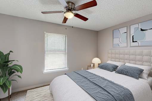 A bedroom with a bed, a ceiling fan, and a potted plant.