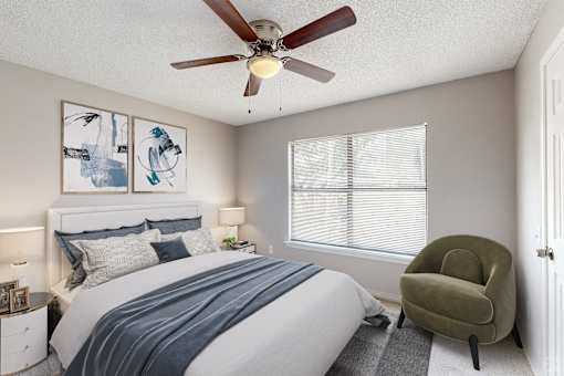 A bedroom with a bed, a chair, and two framed pictures on the wall.